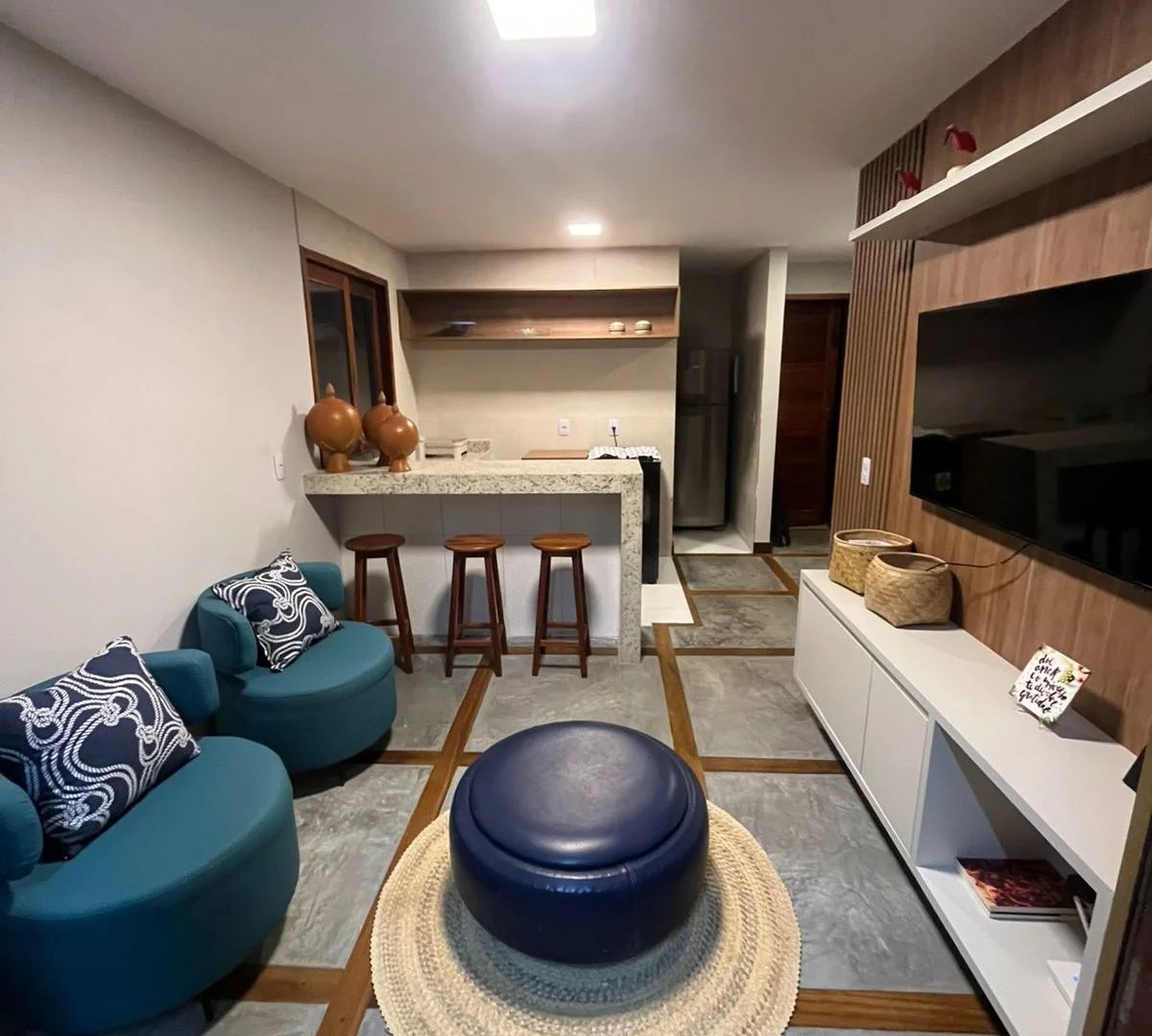 Sala e cozinha nos Chalés Barra Grande, com móveis azuis.