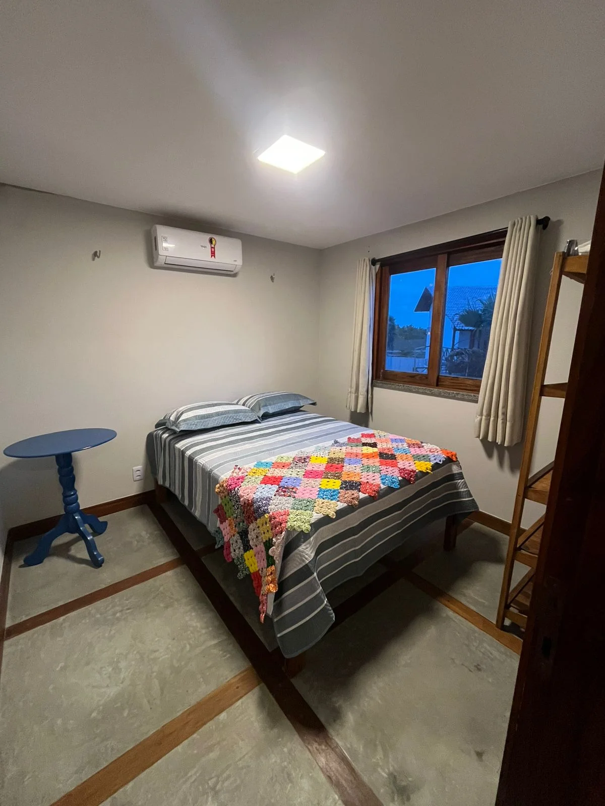 Quarto nos Chalés Barra Grande com cama de casal e colcha listrada.